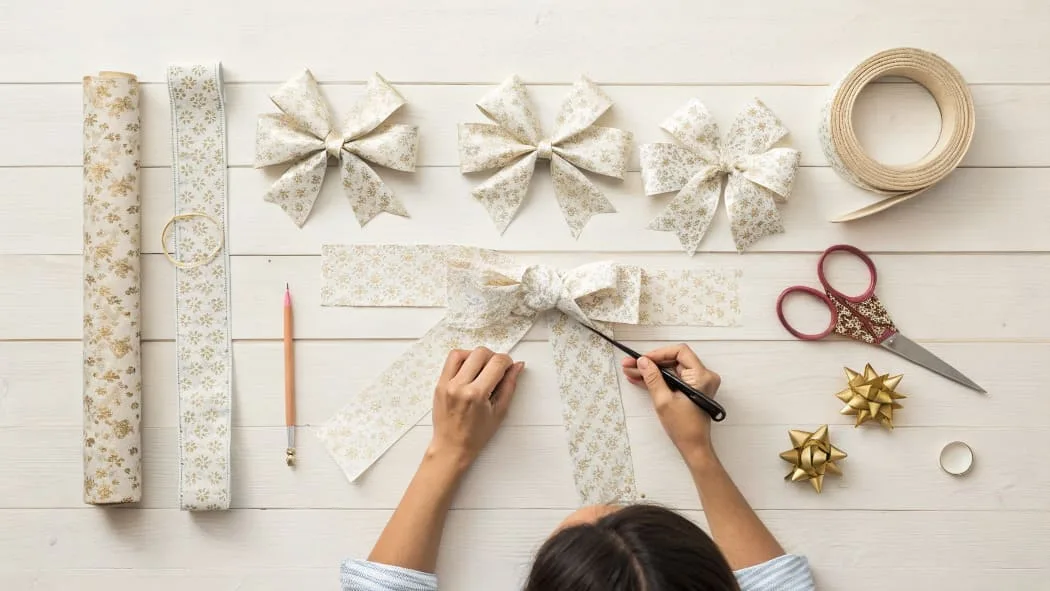 A handmade gift bow made from colorful wrapping paper sitting on a wooden table.