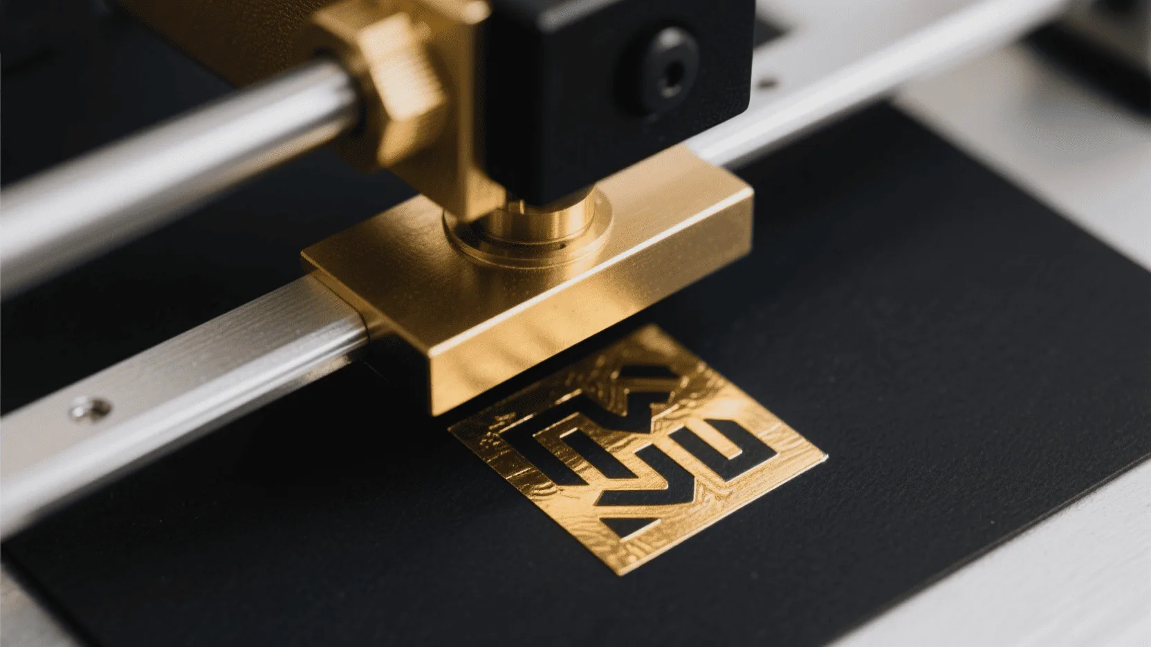 A detailed macro shot of a gold foil stamping machine pressing a logo onto a piece of black paper.