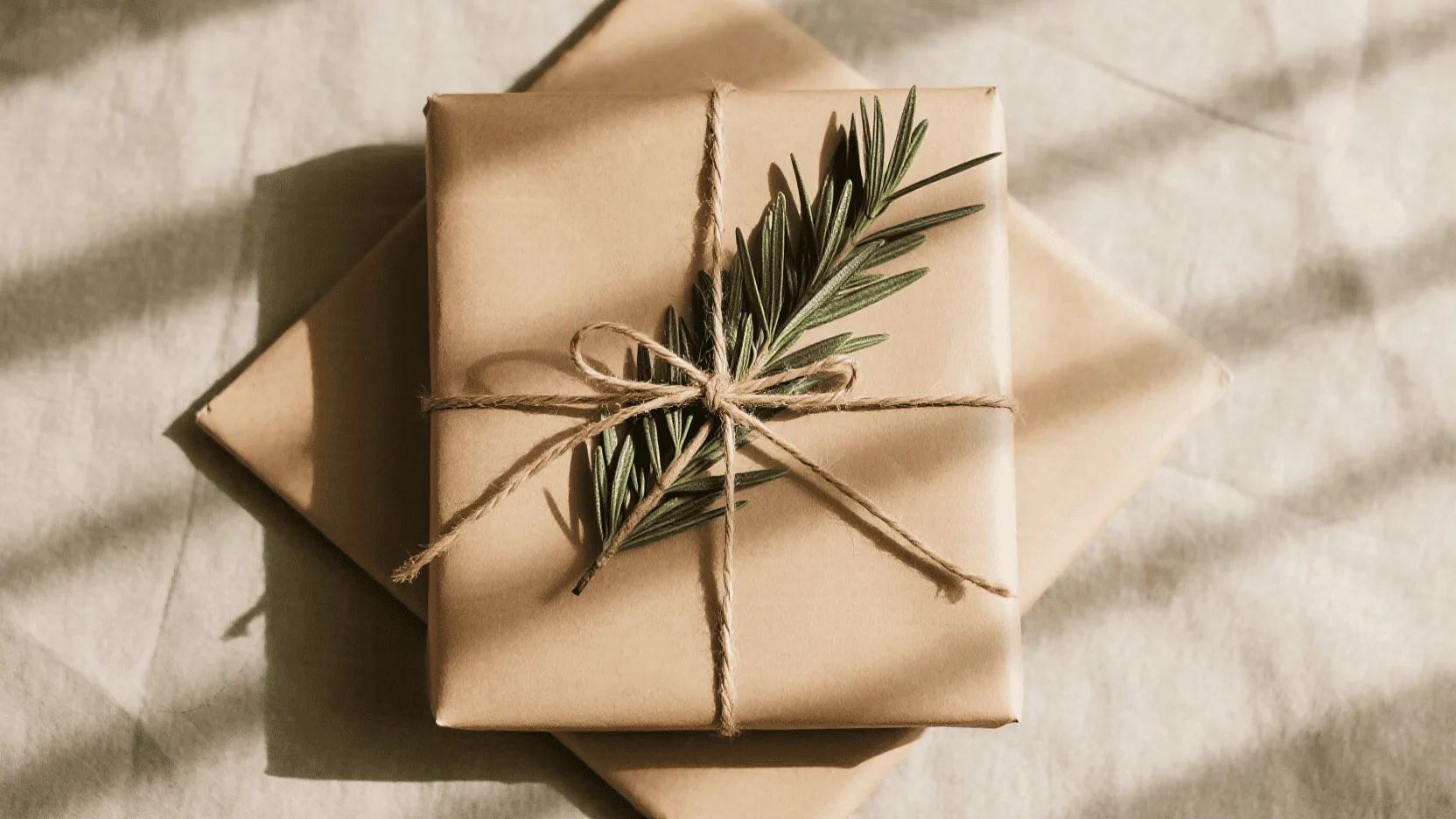 A beautifully wrapped gift in minimalist kraft paper with a simple green sprig.
