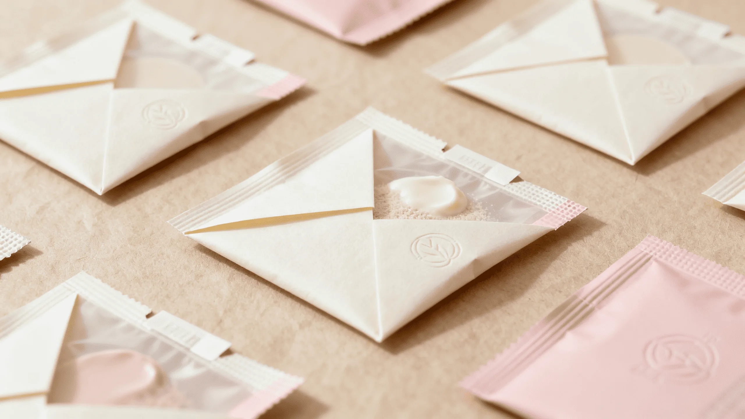 A collection of small, elegant paper-based sachets or pods for single-use cosmetic products.