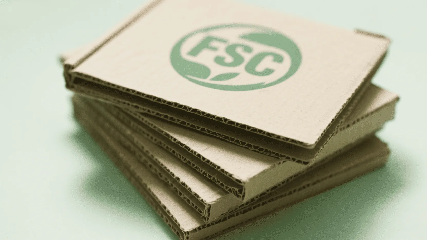 A stack of flattened cardboard boxes showing an FSC (Forest Stewardship Council) logo stamped on them.