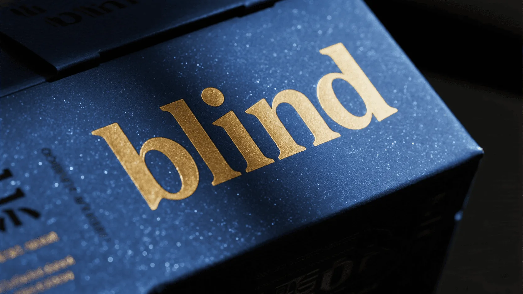 Side-angle view of a blind embossed logo on a deep blue glitter paper, with light catching the raised texture.