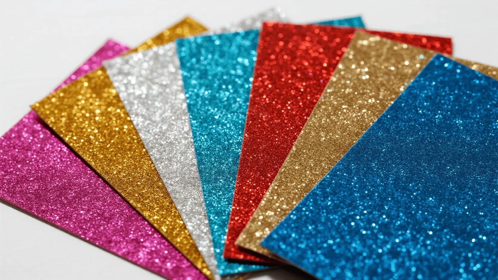A close-up of various glitter paper color swatches, showing different textures and shades of sparkle.