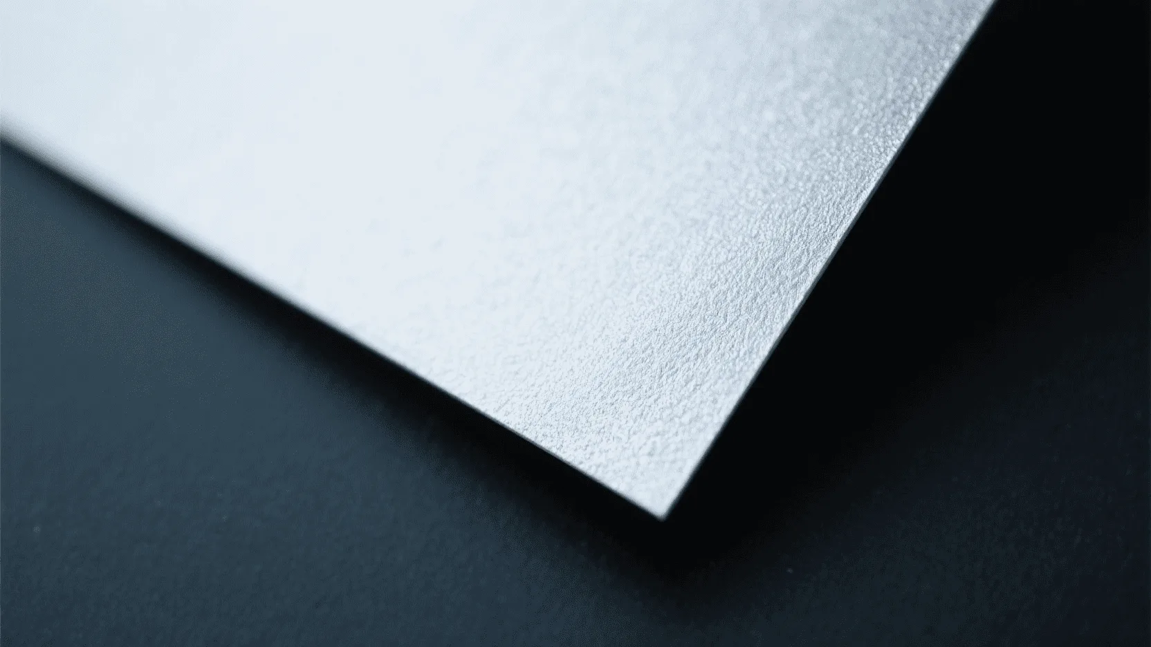 A close-up macro shot of a textured, silver paper that has a fabric-like weave and soft look.