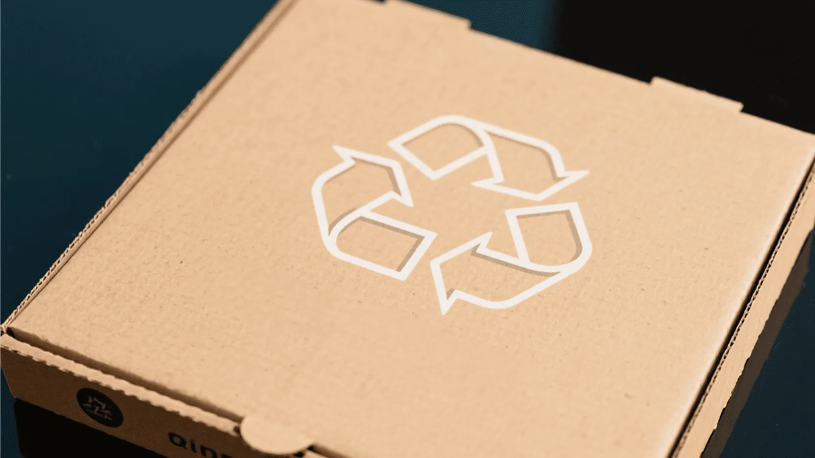 A pizza box featuring a clear recycling symbol and a message encouraging customers to dispose of it responsibly.