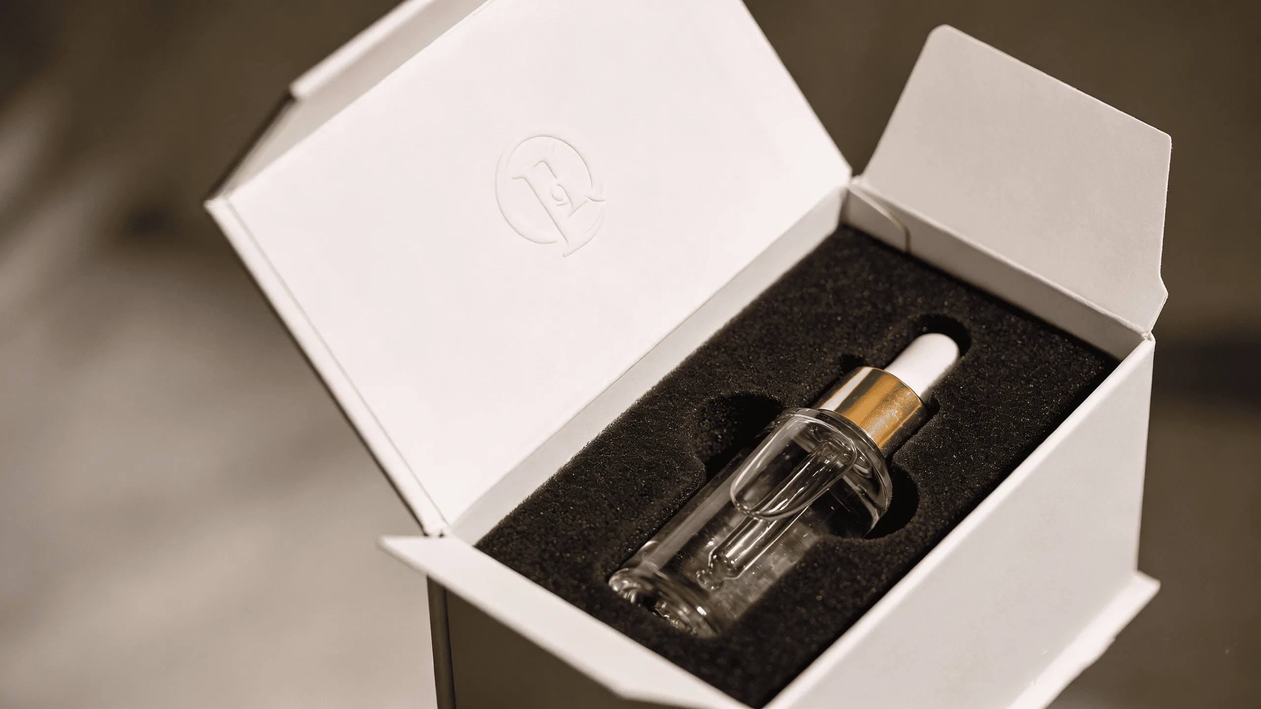 A luxurious white rigid flip-top box opening to reveal a high-end cosmetic product nestled in a custom insert.