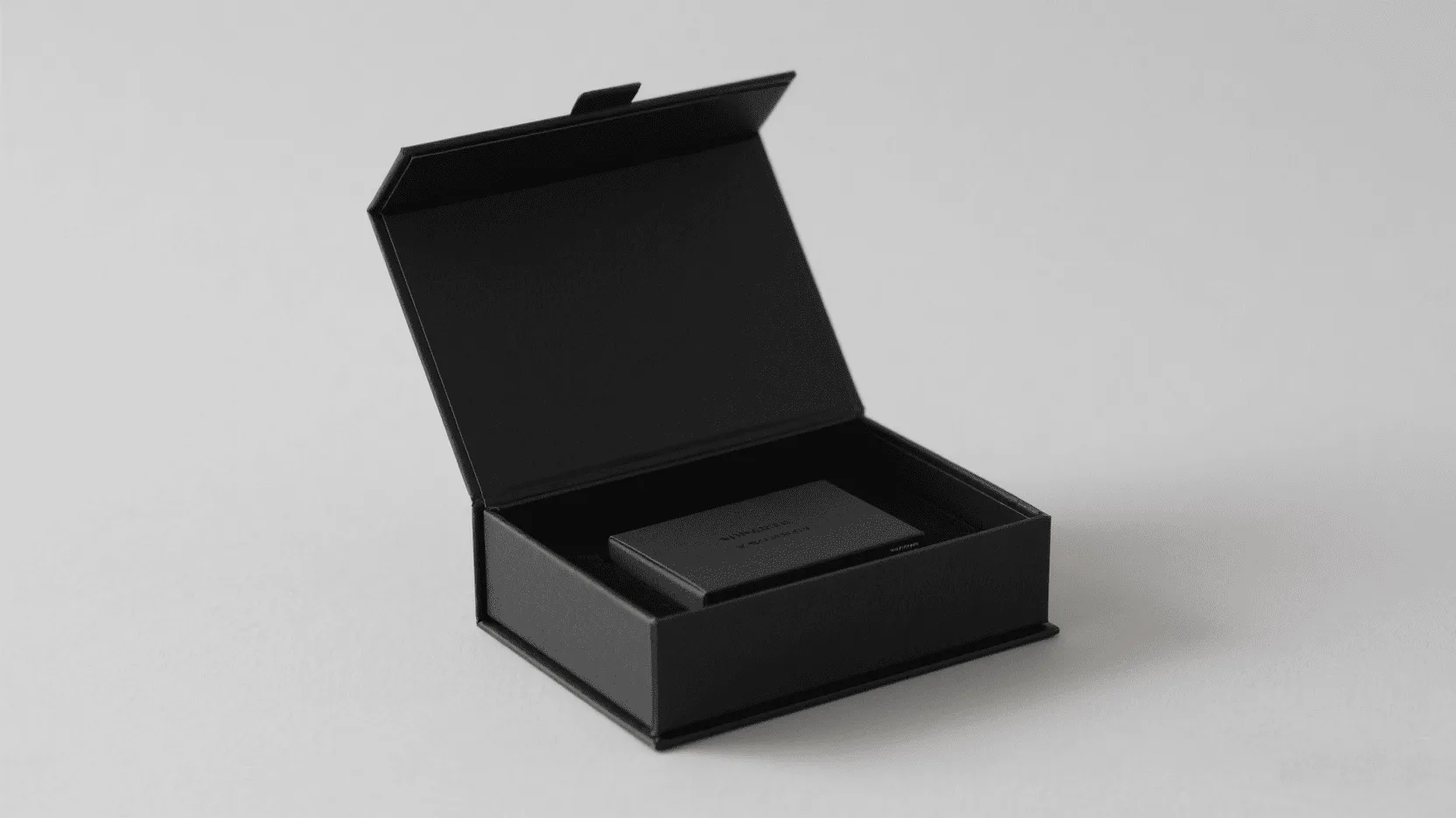 A sleek, matte black magnetic fold gift box opening with a satisfying snap, revealing a product inside.
