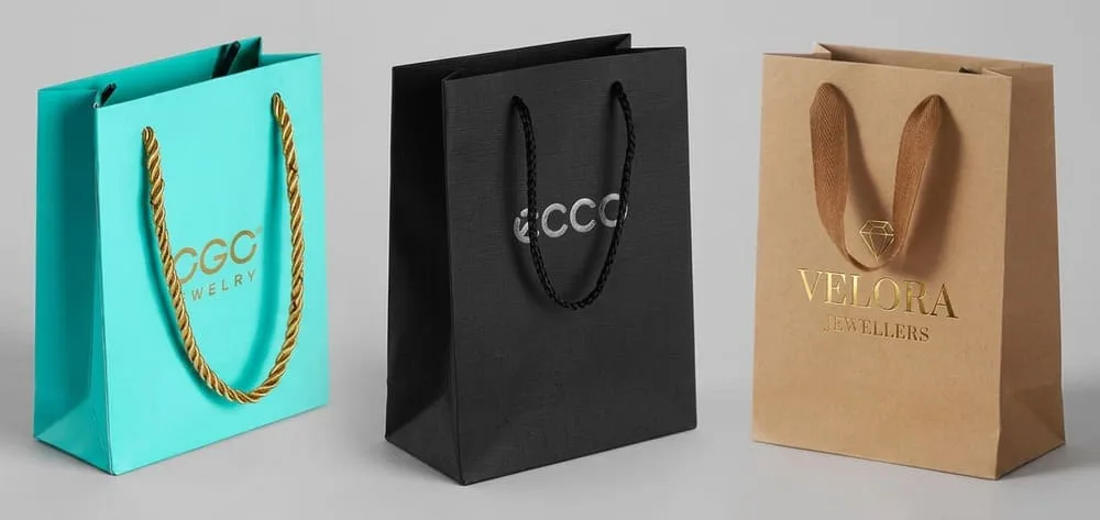 A side-by-side comparison of three jewelry bags made from kraft paper, coated art paper, and textured specialty paper