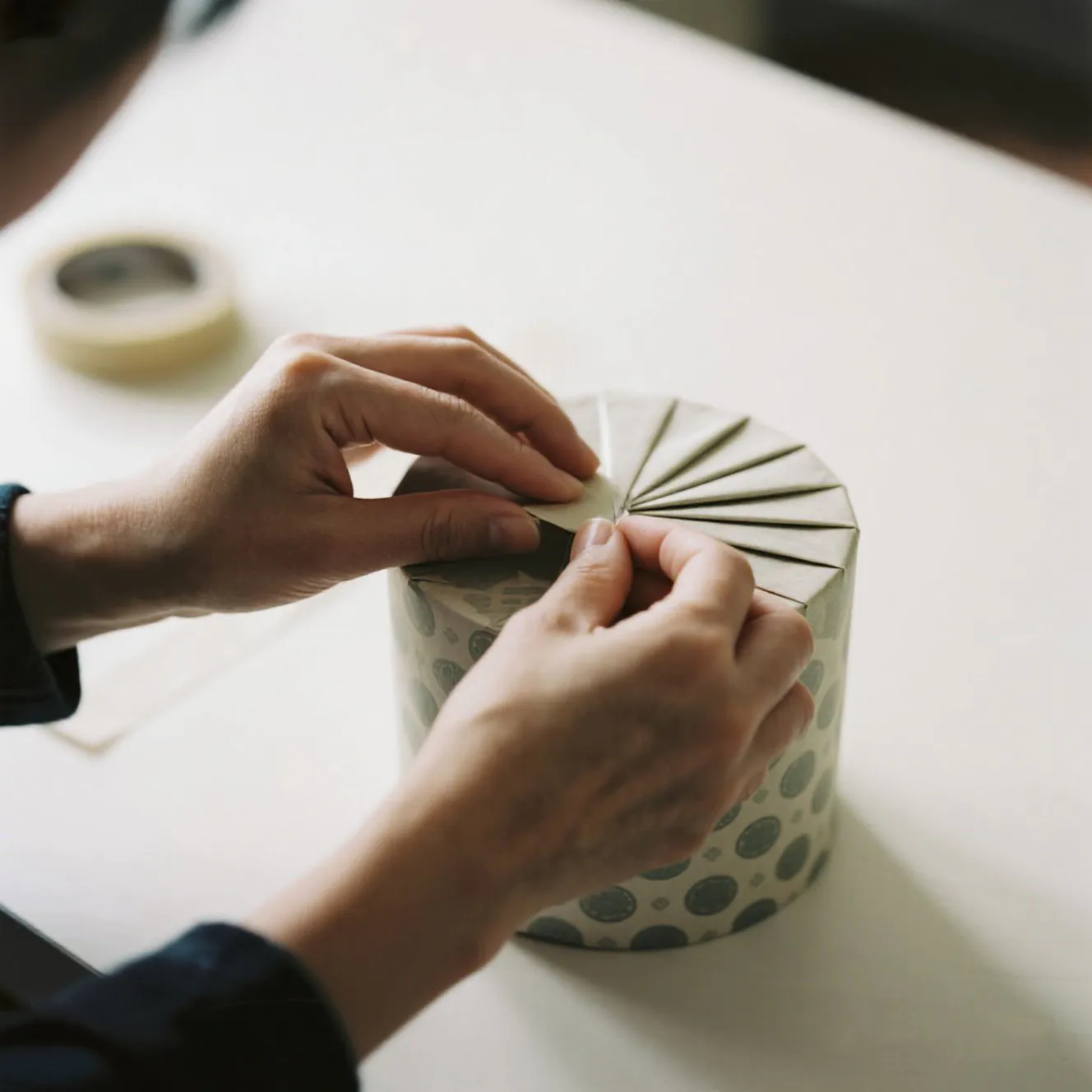 A beautifully wrapped cylindrical gift with pleated ends
